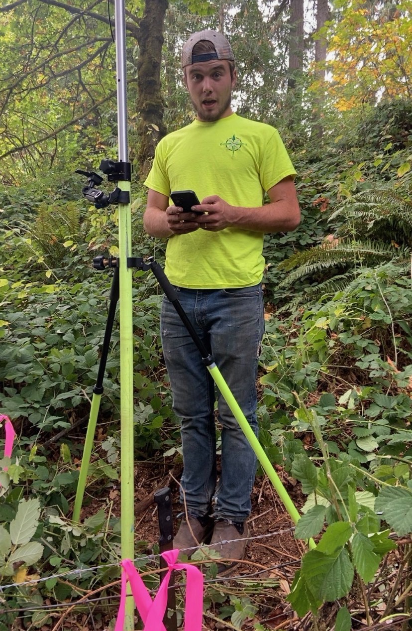 KLS surveyor with field equipment among Northwest vegetation