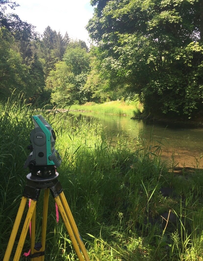 Total station set up beside a wooded creek